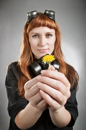 Redhead girl holding yellow dandelion in her hands over gray. Focus on hands.の写真素材