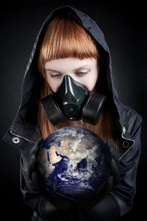 Girl in hood holding earth in her hands over dark background. の写真素材