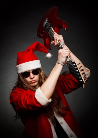 Crazy Santa posing with electric guitar over dark backgroundの写真素材