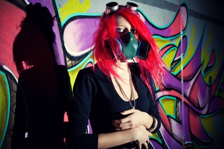 Redhead girl in gasmask posing over wallの写真素材