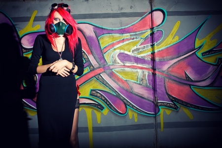 Redhead cyber goth girl in gasmask posing over wallの写真素材
