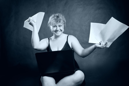 funny blondie with paper and laptop posing over blueの写真素材