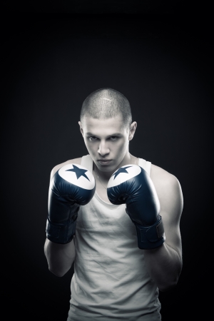 Young aggressive boxer posing over dark backgroundの写真素材