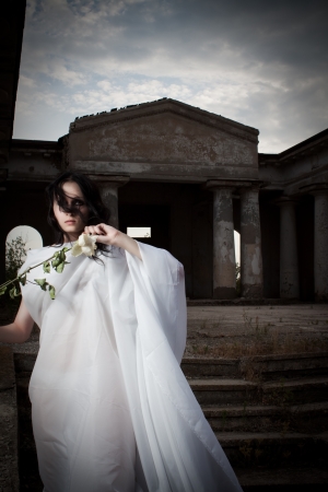 Pretty gothic girl in white clothes posing with roseの写真素材