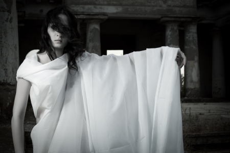 Pretty girl in white clothes on an old cemeteryの写真素材