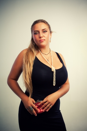 Young luxurious woman with purse in black dress posing over white backgroundの写真素材