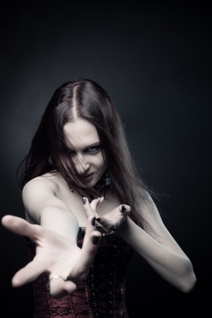 Seductive vampire in red corset posing over dark backgroundの写真素材