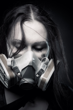 Pretty girl in gasmask posing over dark backgroundの写真素材