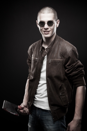 Young man in sunglasses with bloody chopper posing over dark backgroundの写真素材