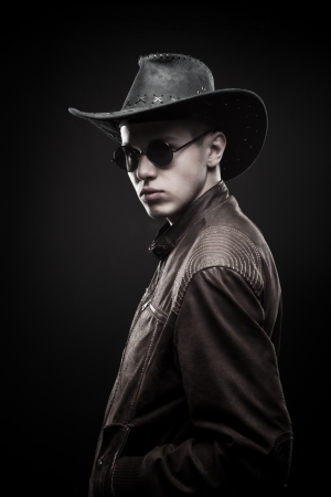 Macho in cowboy hat and jacket posing over dark backgroundの写真素材