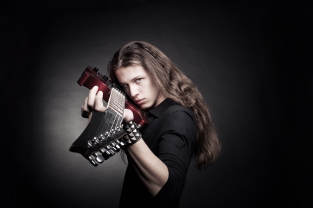 Heavy metal guitarist with electirc guitar posing over dark backgroundの写真素材