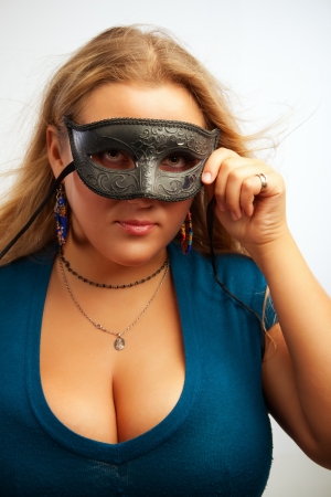 Seductive young woman in mask posing over white backgroundの写真素材