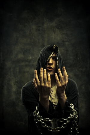 Miserable prophet with hands in chains posing over dark backgroundの写真素材