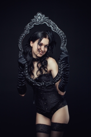 Attractive gothic girl in black corset and panties with frame over dark backgroundの写真素材