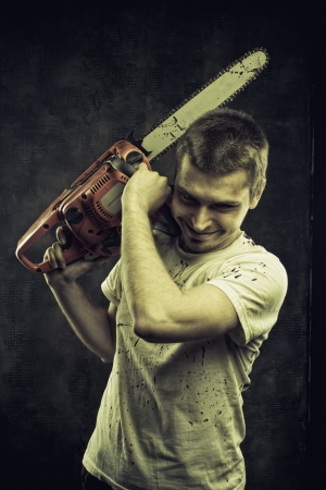 Mad maniac with bloody chainsaw over grunge backgroundの写真素材