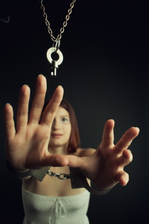 Frustrated bounded cute girl trying to grab the key over blackの写真素材