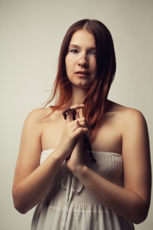 Beautiful girl with a rosary on her hands over white backgroundの写真素材