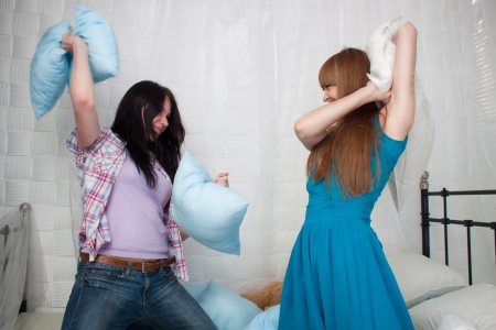 Two girls having a pillow fight at home の写真素材
