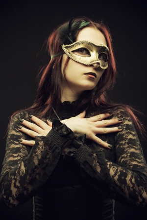 Seductive girl in mask posing over black backgroundの写真素材