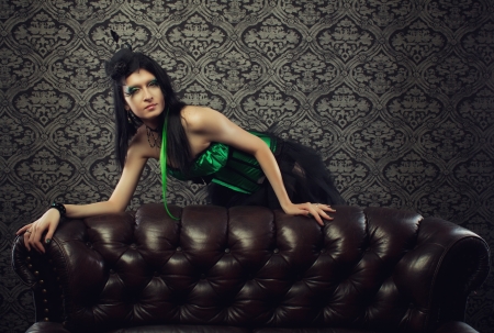 Pretty fairy in green corset stands behind a divanの写真素材