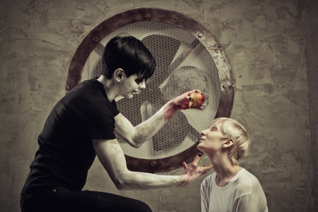 Scary guy in black with apple and mad girl in white in a cell of an asylum の写真素材