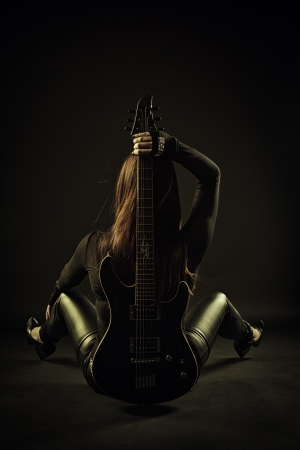 Pretty rocker sitting on the floor with guitar  