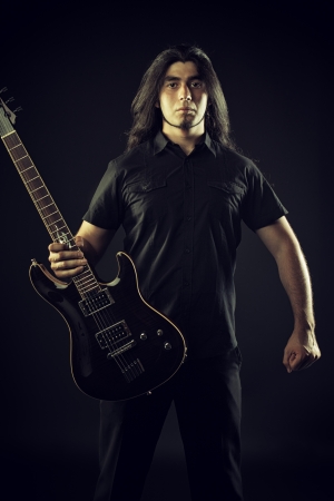 Brutal heavy metal guitarist  with black electric guitar over dark backgroundの写真素材
