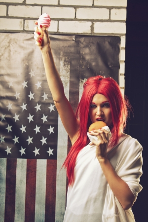 Young redhead woman dressed as the Statue Of Liberty with ice creamand hamburgerの写真素材