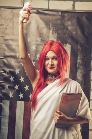Young redhead woman dressed as the Statue Of Liberty with ice cream and comicsの写真素材