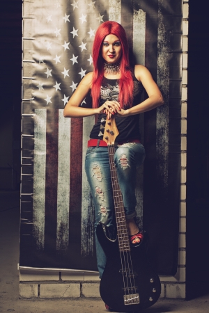 Redhead rock and roll star with bass guitar over american flagの写真素材