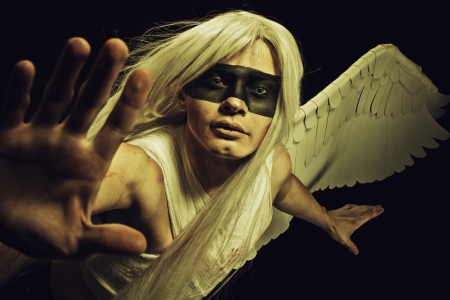 Handsome one-winged angel posing over dark backgroundの写真素材