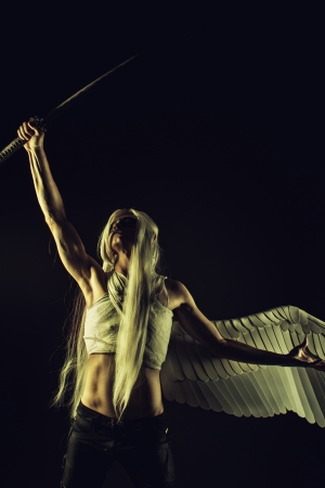 Mighty and brave angel posing with katana over dark backgroundの写真素材