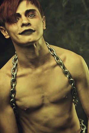 Naked redhead goth with chains over dark backgroundの写真素材