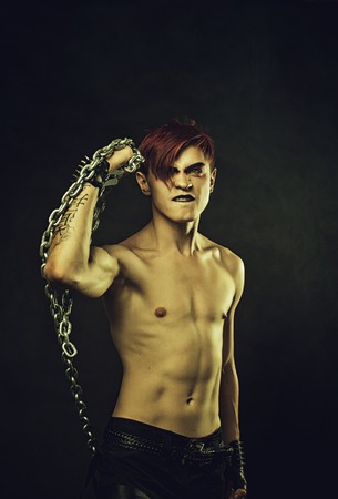 Browny redhead young man with chains posing over dark backgroundの写真素材