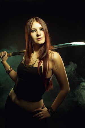 Strong powerful girl posing with sword over dark backgroundの写真素材