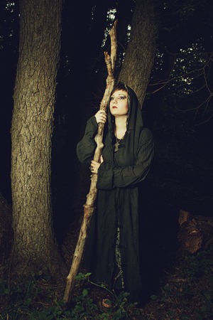 Girl in hood with staff in the forestの写真素材