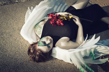 Dead pretty angel laying on the ground with flowersの写真素材