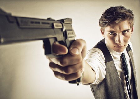 Serious young gangster aiming over white backgroundの写真素材