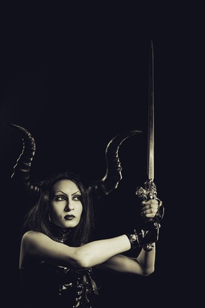 Seductive horned gothic girl in latex with sword over dark backgroundの写真素材