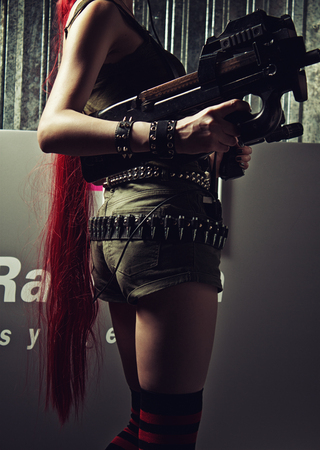 Redhead young lady posing with pistol and fn p90.の写真素材