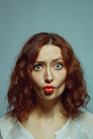 Young pretty girl with a funny expression over grey backgroundの写真素材