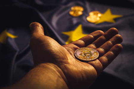 Golden bitcoin in a hand over EU flagの写真素材
