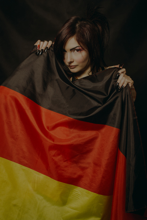Asian girl posing with flag of Germany over dark backgroundの写真素材