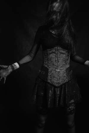 Gothic girl in red corset posing over dark background