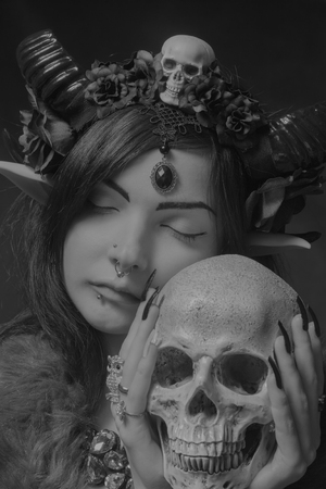 Horned asian cute girl with skull posing over dark backgroundの写真素材