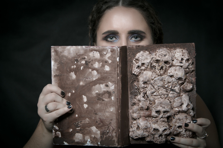 Girl with Necronomicon posing over dark backgroundの写真素材