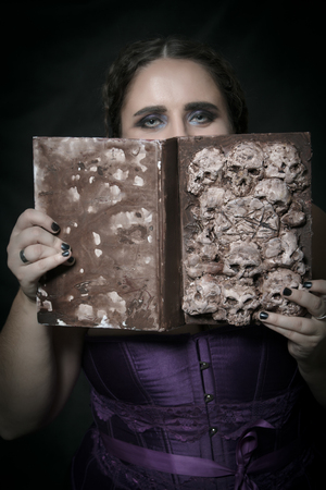 Girl with Necronomicon posing over dark backgroundの写真素材