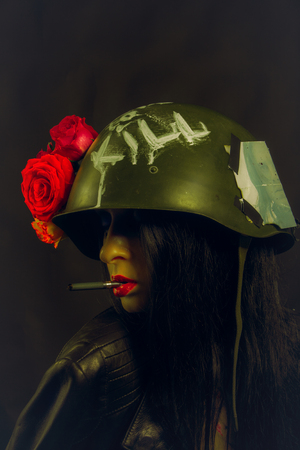 Sexy glamour girl in helmet smoking cigarette over dark backgroundの写真素材