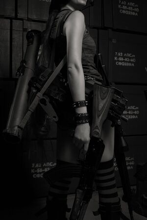 Redhead girl with weapons posing in a storageの写真素材