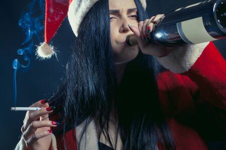 Pretty seductive girl in Santa's costume drinking over dark backgroundの写真素材